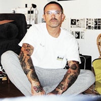 a man sitting on the floor with tattoos